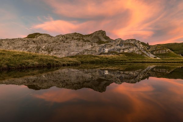 Red sky above mountain hut and lake